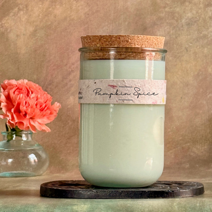 Candle labeled 'Pumpkin Spice' with a pink flower in the background